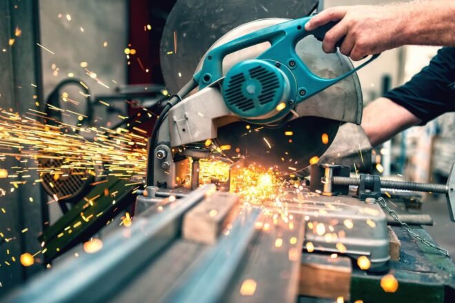 industrial worker using a  compound mitre saw with circular blade for cutting metal and plastic